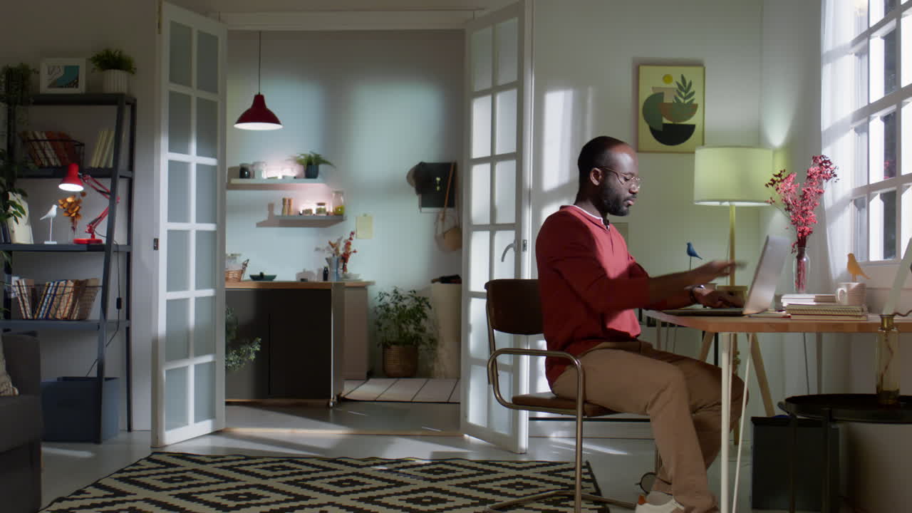 Black Man Walking in Room and Working on Laptop