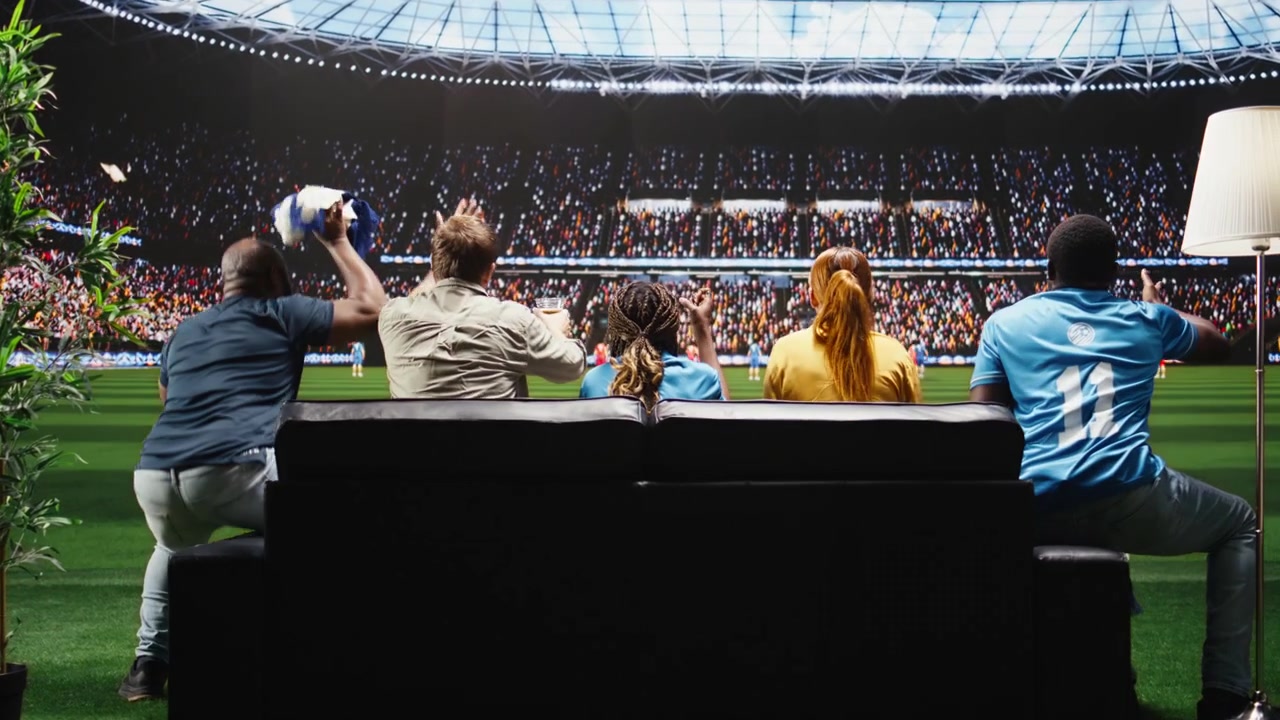 Rear view of soccer supporters on couch upset by goal on interactive broadcast