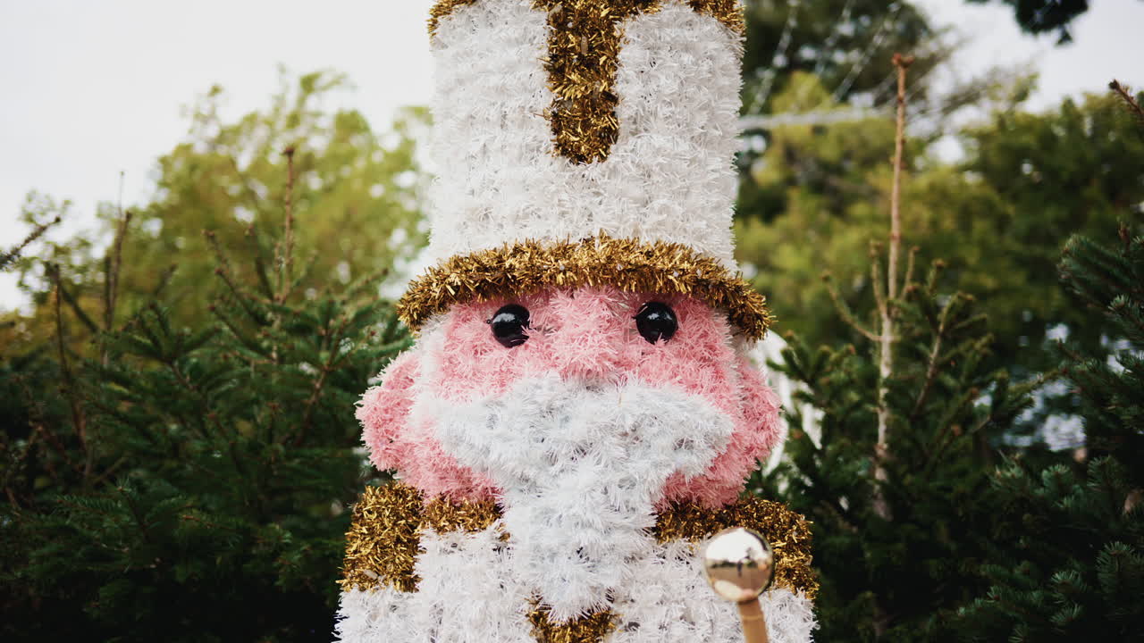 Decorative Christmas nutcracker soldier figure displayed outdoors with trees in the background