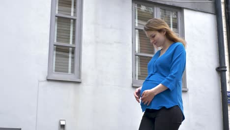 Pregnant-caucasian-woman-strolling-down-mews-street-in-london