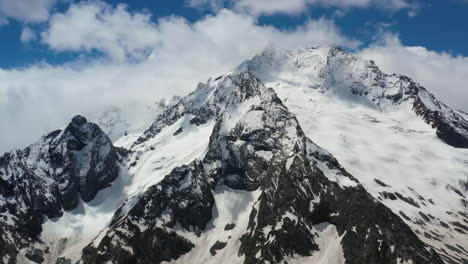 Air-flight-through-mountain-clouds-over-beautiful-snow-capped-peaks-of-mountains-and-glaciers.