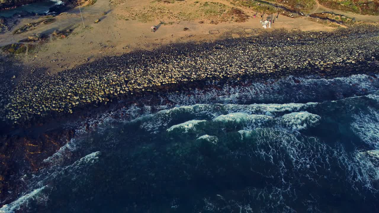 Drone's backward view of waves crashing on the beach
