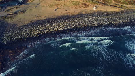 la vista hacia atrás del avión no tripulado de las olas que se estrellan en la playa