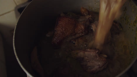 verter ingredientes líquidos en una olla para preparar &quot;arroz con pato