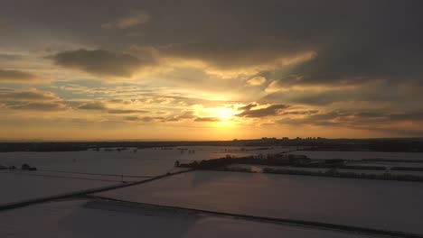 Toma-Aérea-De-Puesta-De-Sol-Con-Campos-De-Nieve-Sombreados-Oscuros-Debajo