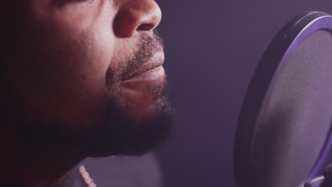 man singing into a microphone in a recording studio