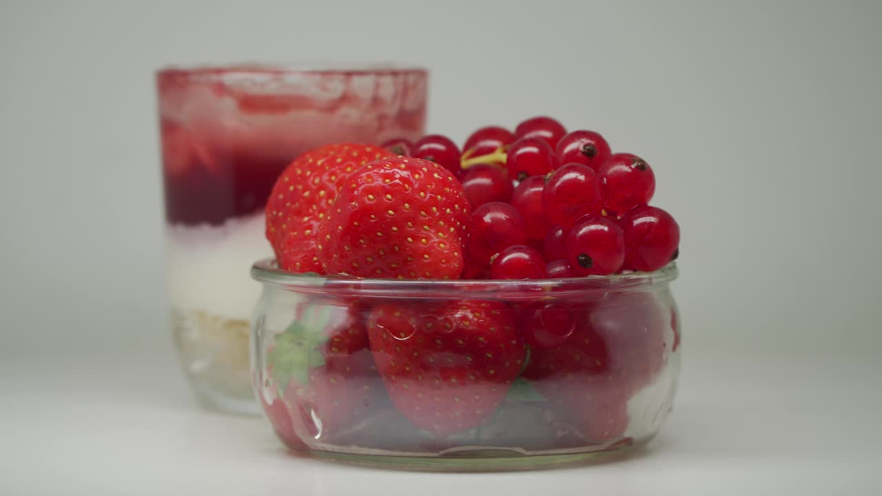 un delicioso pastel de fresas en un vaso y algunas fresas y grosellas rojas en un recipiente transparente - primer plano