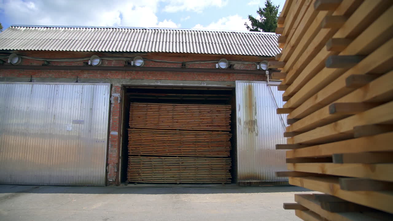 Brick stone warehouse with opened doors. The premise of the barn filled with timber sticks.