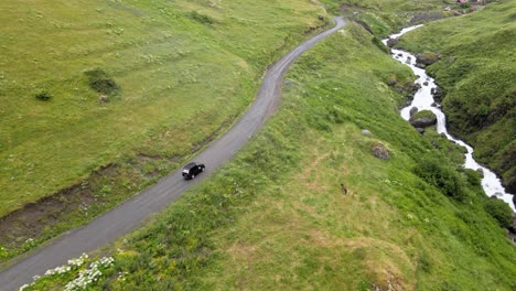 drone-shot-of-Car-driving-in-nature-in-the-middle-of-nowhere-river-mountains