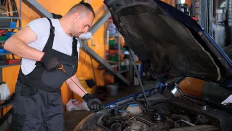 mechanic checking car engine oil level in a garage
