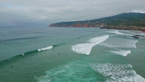surfers catching ocean waves at scenic coastline aerial view. rugged cliffs