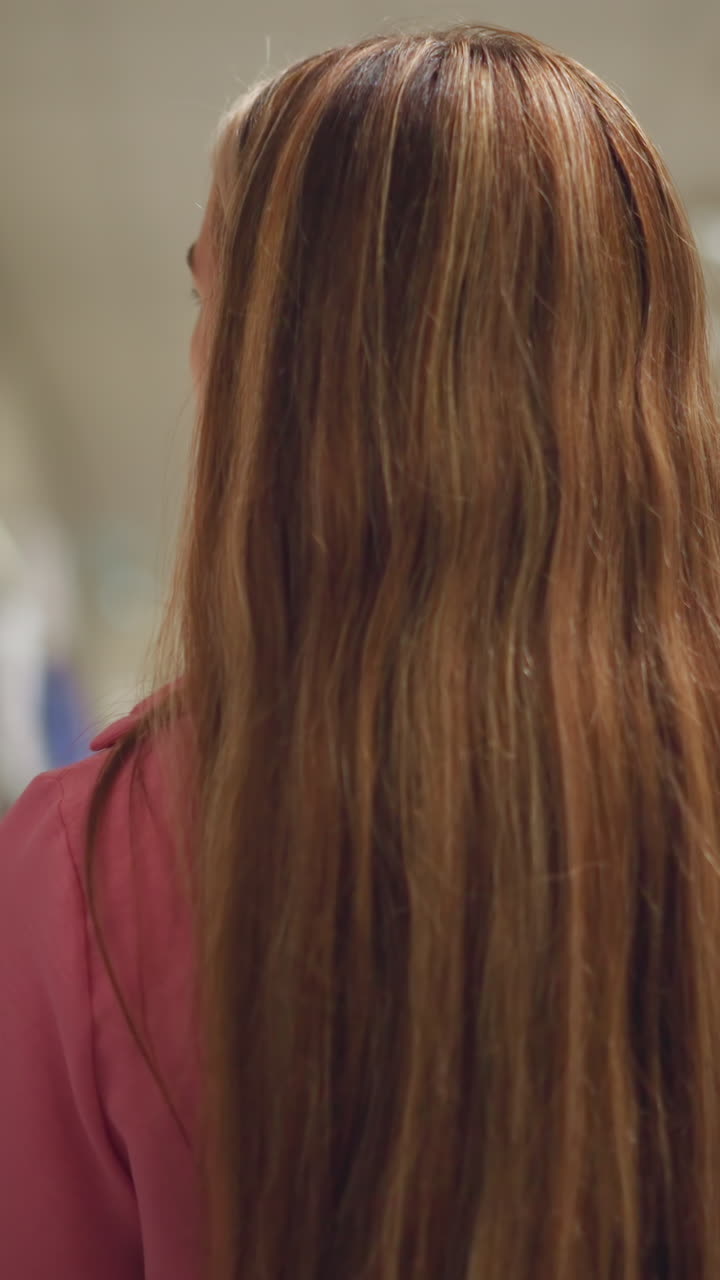 dama de ropa rosa camina a través de una tienda de boutique, mirando a la derecha en una variedad de ropa colgada dispuesta en secciones, la tienda está bien iluminada, con la ropa bien organizada