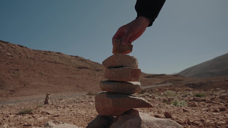 Placing rock on stone cairn in arid desert valley of Morocco symbolizing balance and patience