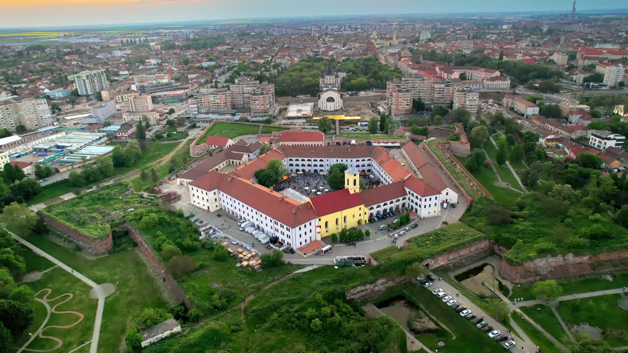 Aerial drone view of Oradea Fortress at sunset, Romania. Multiple people inside the fortress, residential district with multiple buildings around
