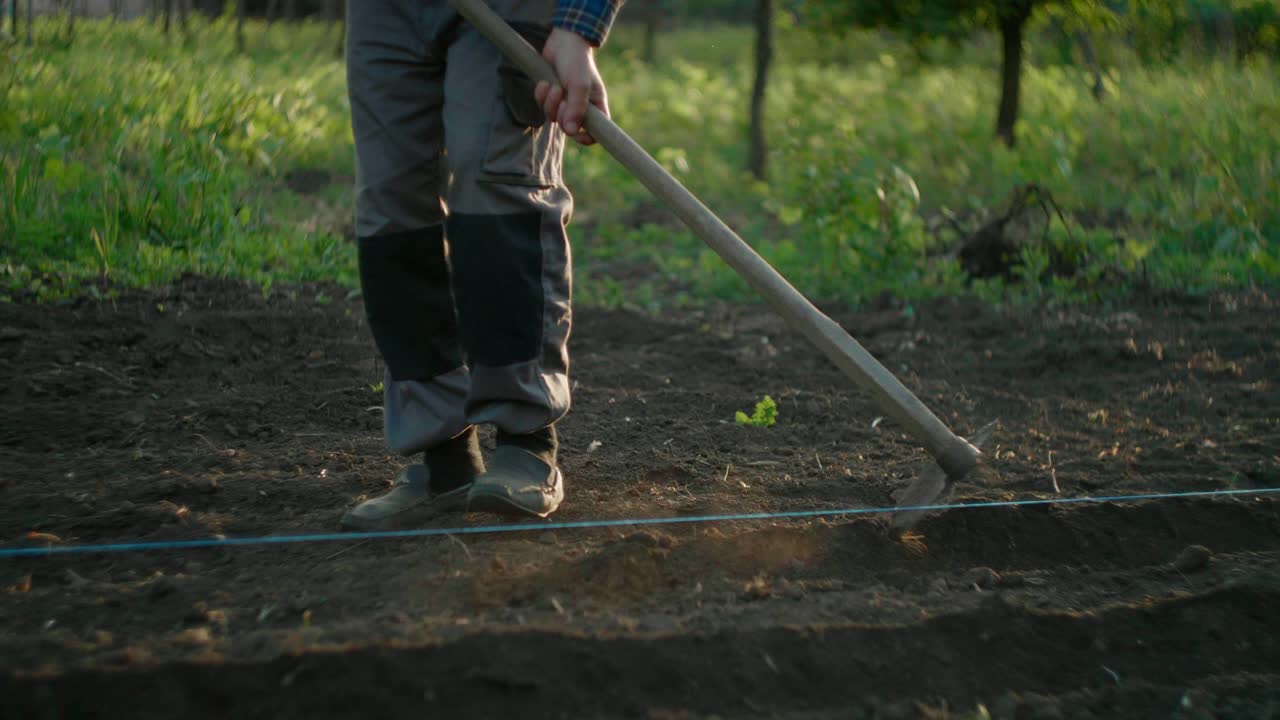 Farmer making lines in the dirt to plant crops