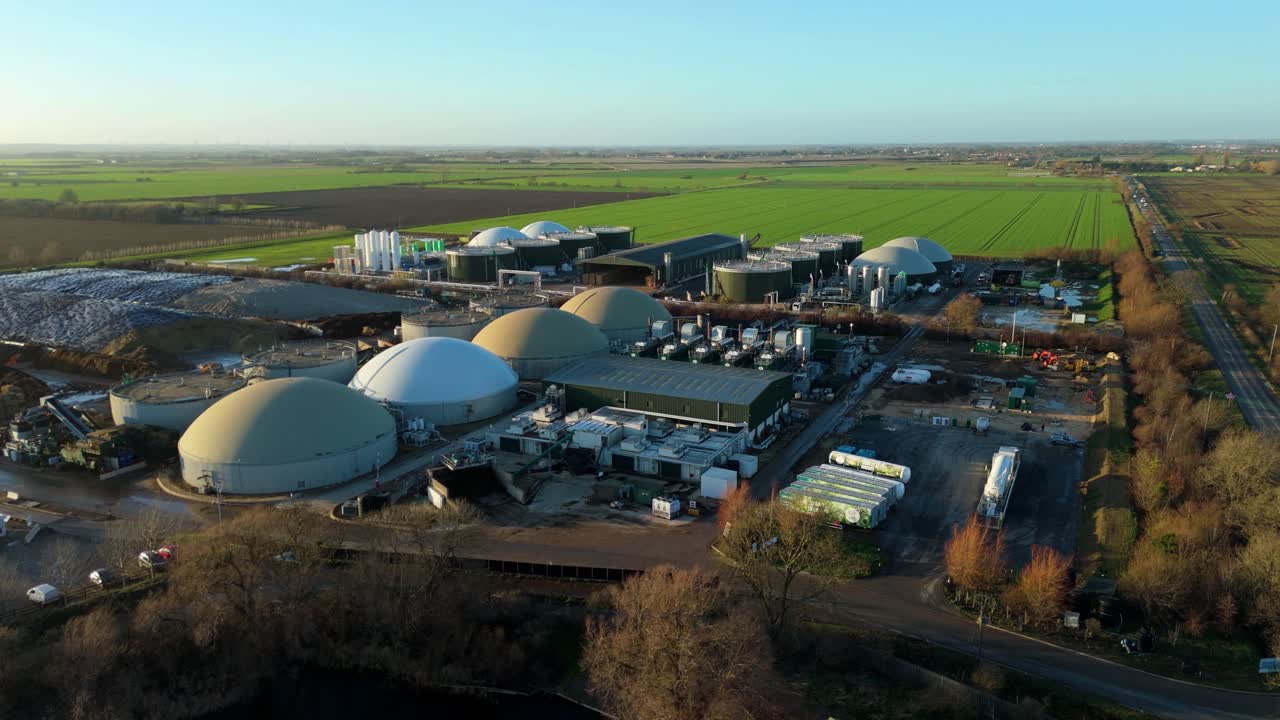 Aerial drone view of a large-scale renewable biogas energy facility near Chatteris, UK, featuring distinctive gas storage domes in golden hour light