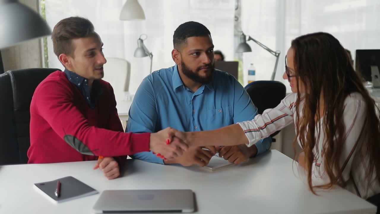 jóvenes seguros de sí mismos estrechando la mano en la oficina.