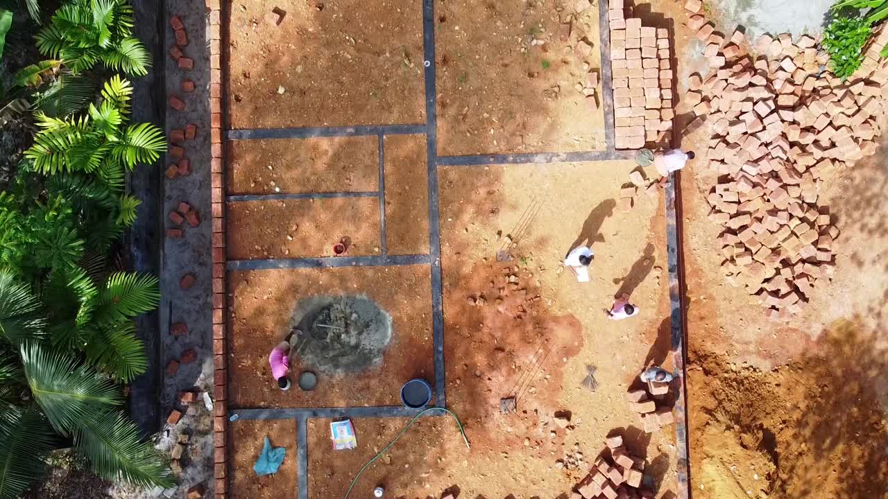 la fundación de la casa, los trabajadores de la construcción trabajan en un sitio de construcción en la india, la construcción de una casa con piedra roja, trabaja usando cemento, vista del cielo