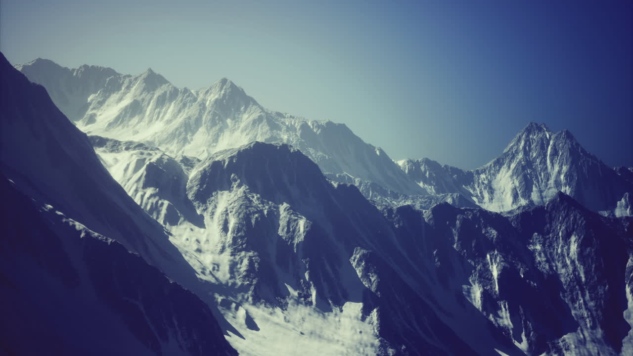 Snow covered mountain range under clear blue sky in bright daylight