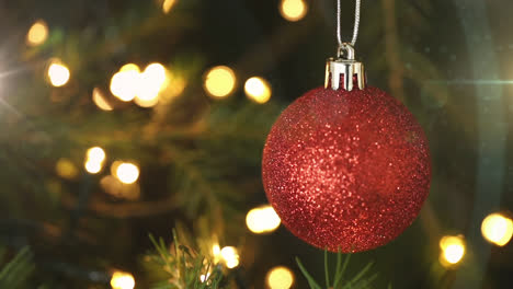 composición digital de puntos de luz contra la decoración de baubles de navidad colgando
