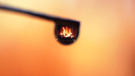 zoom in shot, single droplet fireplace reflection, flames burning background