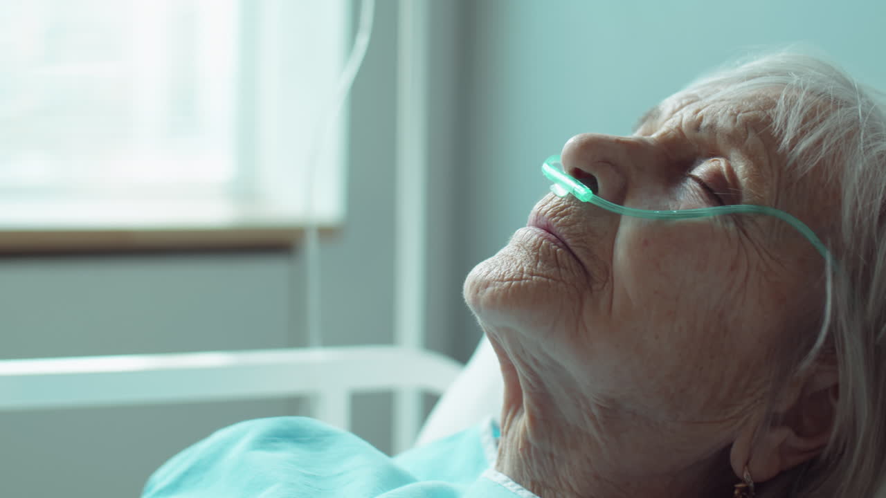 Paziente anziano sdraiato con gli occhi chiusi in ospedale.