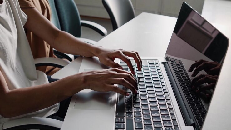 Persona che digita sulla tastiera di un laptop in un ambiente d'ufficio.