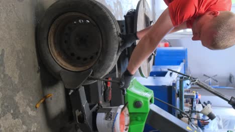 auto mechanic working on a car tire in a workshop