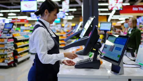 supermarket employee assisting at self-checkout counter