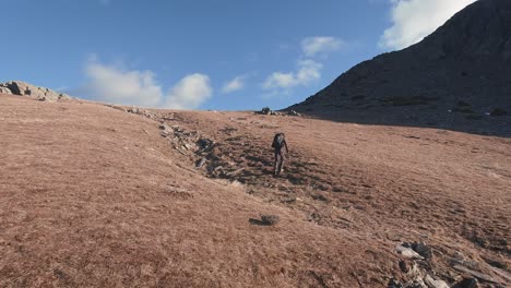 back view of young hiker going uphill in mountain range near madrid, sierra norte, spain