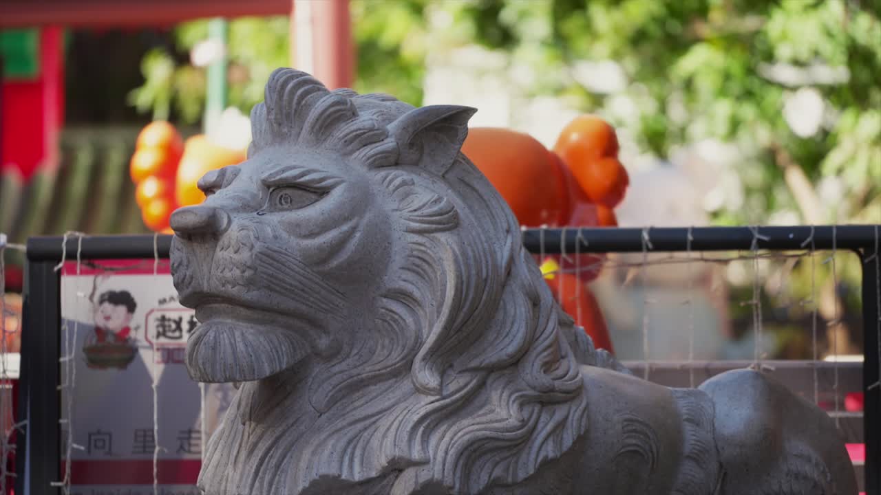 Close-up genggam kepala patung singa penjaga batu di Sydney Chinatown, dengan etalase dan latar belakang jalanan yang tidak fokus