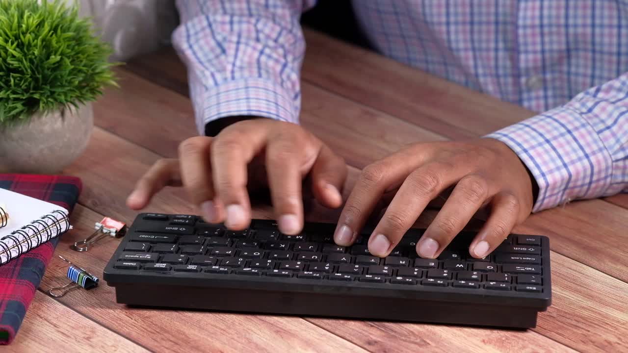 Person Typing on a Keyboard at a Wooden Desk