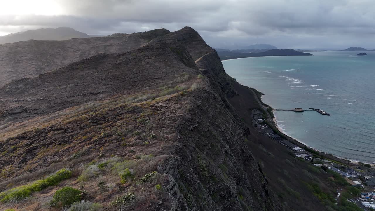 Drone che sorvola la cima di una montagna a Oahu, nelle Hawaii, digradante verso il mare con illuminazione spettacolare. Incredibile scenario tropicale dell'isola, costa frastagliata e vivaci viste sull'oceano, filmato aereo cinematografico