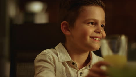 Boy-making-toast-during-dinner.-Cheerful-kid-clicking-glasses-with-family