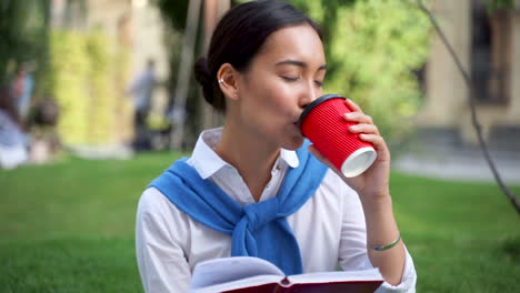 frau, die ein buch liest und draußen einen kaffee trinkt