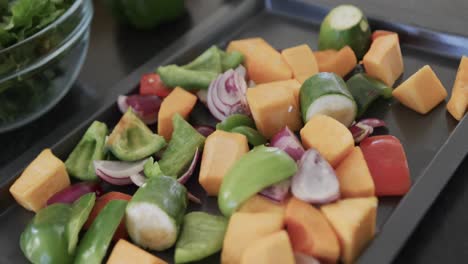 close up of kitchen countertop with chopped vegetables in baking tray, slow motion