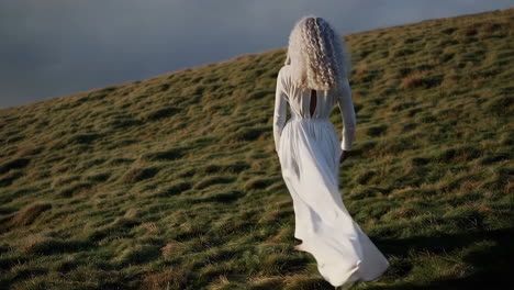 woman in white dress walking on a hill