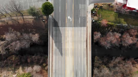 aerial shot zooming down on vehicles traveling on creek overpass in california