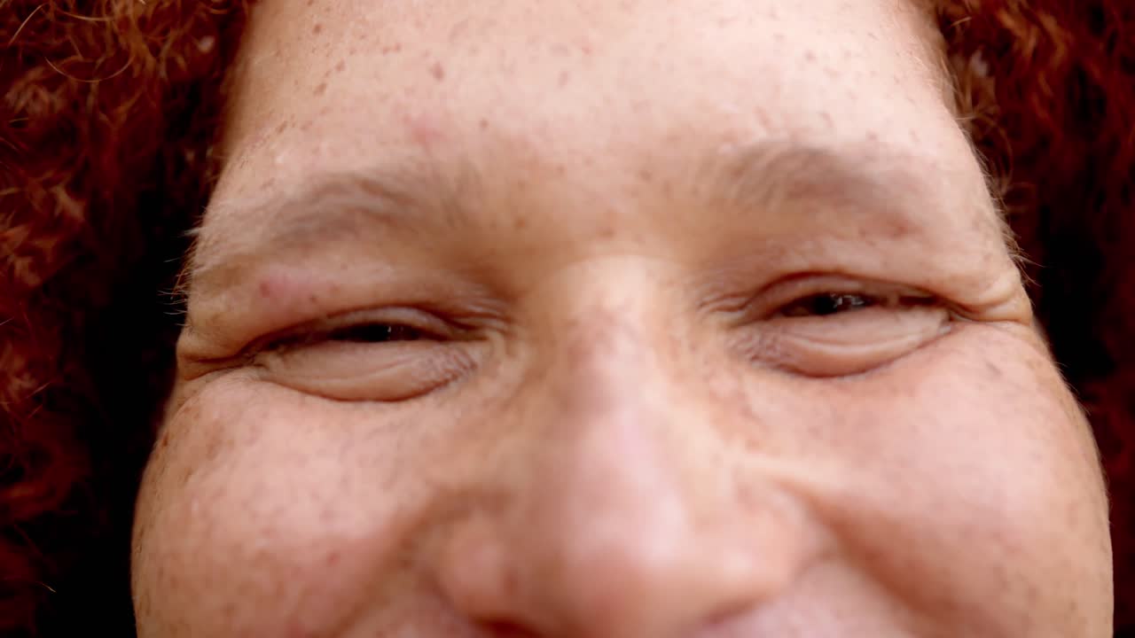 retrato en primer plano de un hombre biracial feliz con pecas, ojos cerrados y sonriente, cámara lenta