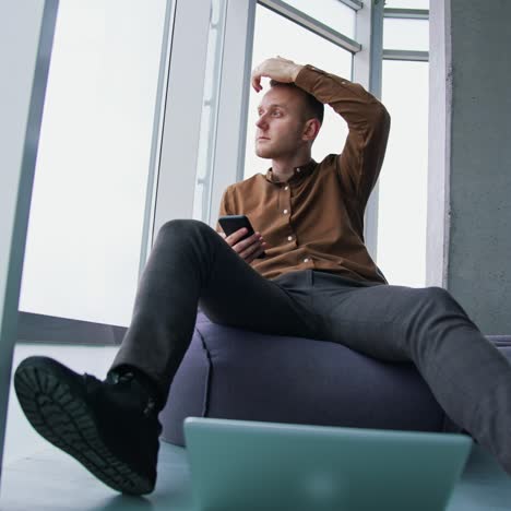 typing business message. young modern businessman using smartphone while sitting in the office