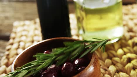 rosemary sprigs falling on the bowl of red olives