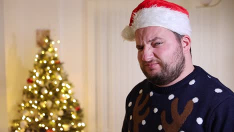 disgusted man frowning while wearing santa hat