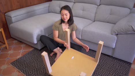 asian woman assembling table in living room