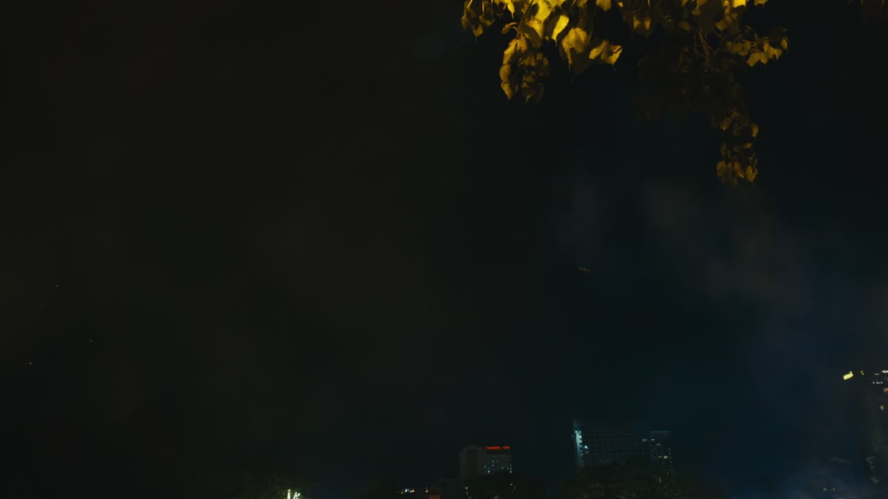 Footage of people lighting fireworks over the Ping River during the Loy Krathong Yi Peng Festival in Chiang Mai, Thailand, capturing a festive and vibrant celebration