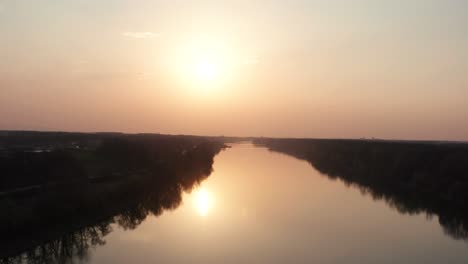 Drone-flying-over-the-river-at-evening-sunset-time