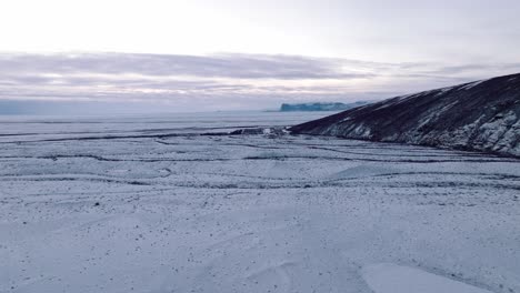 aerial landscape view over skaftafellsjokull glacier surrounding mountains, in iceland, covered in snow, at dusk