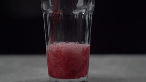 pouring glass full of red carbonated fizzy drink soda