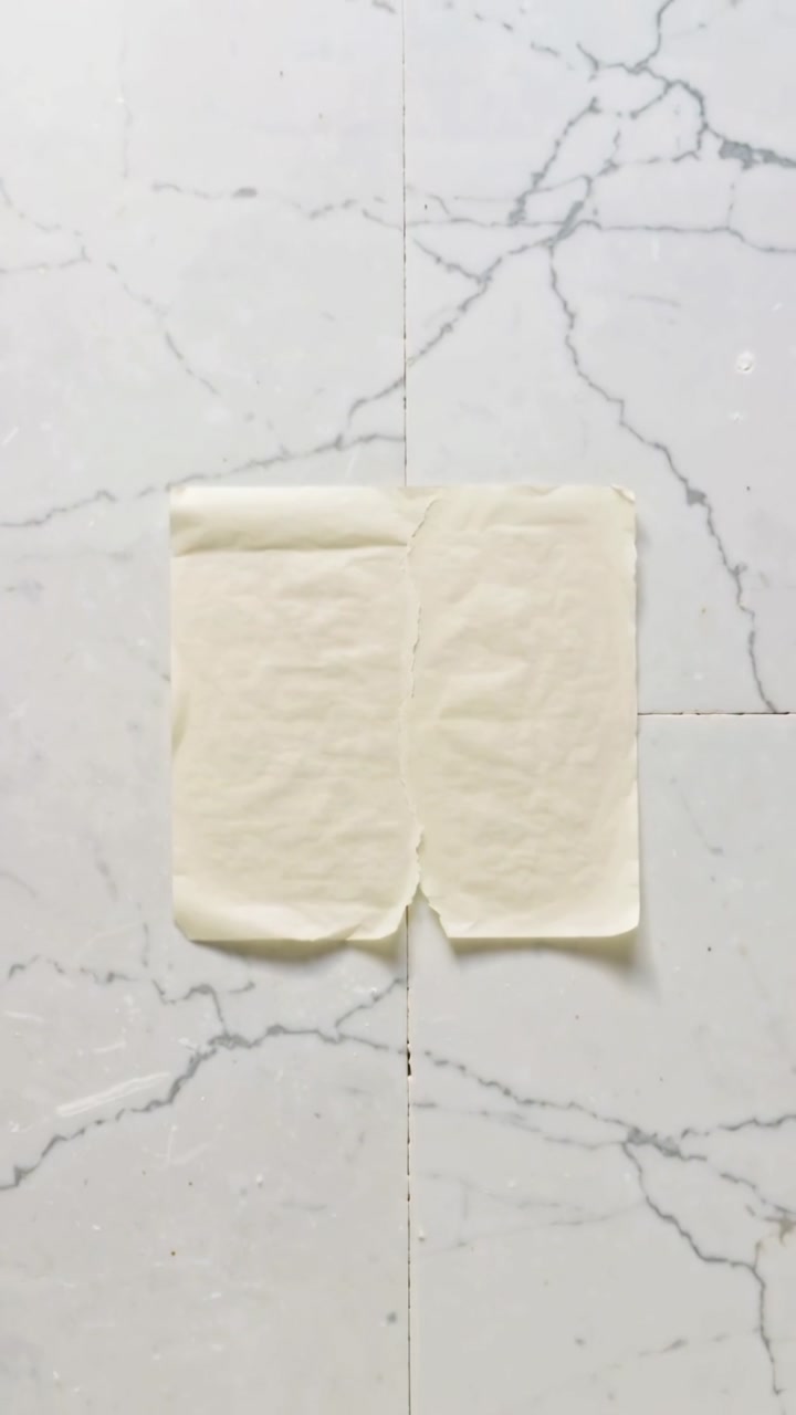 Vertical video: Camera pulling back shifting upward revealing dough slab and marble-look tile veins
