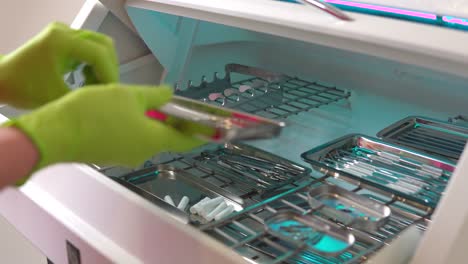 close up shot of hands in gloves taking instruments from the box for dental instruments disinfection. ultraviolet sterile chamber. shot in 4k