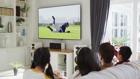 Composite-of-happy-family-sitting-at-home-together-watching-baseball-game-on-tv